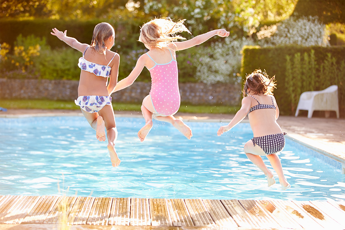 Fröhliche Kinder springen in den Pool