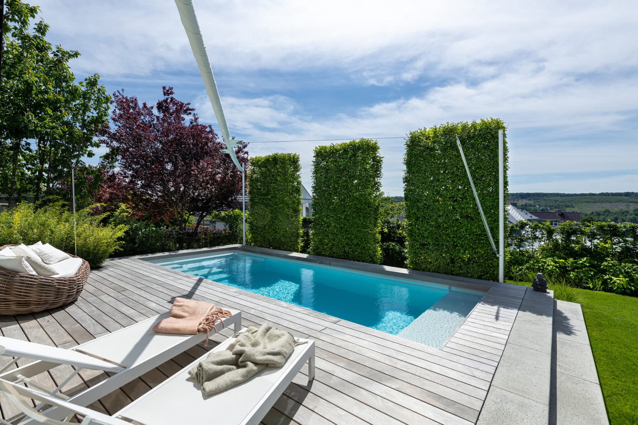 20220603_GvE_TSC7172-s Moderne Terrasse mit einem kleinen Pool, Liegen und grünen Pflanzen im Hintergrund.